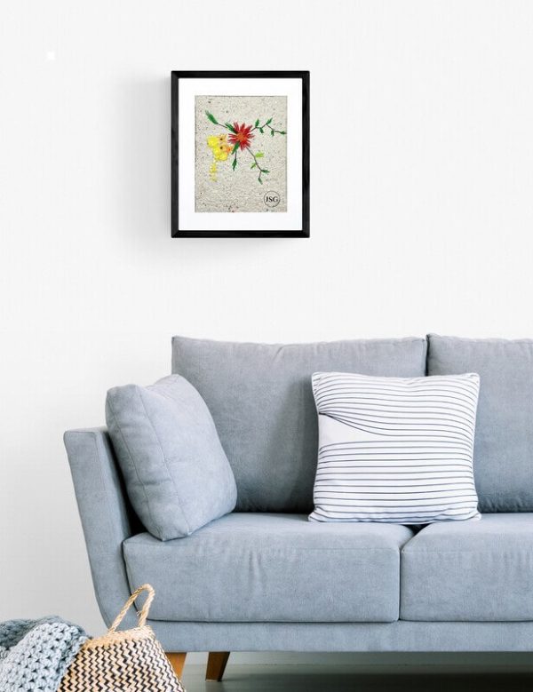 artwork of red yellow and orange flowers embroidered on homemade paper displayed in a black frame hung on the wall of a living room with a blue couch flower
