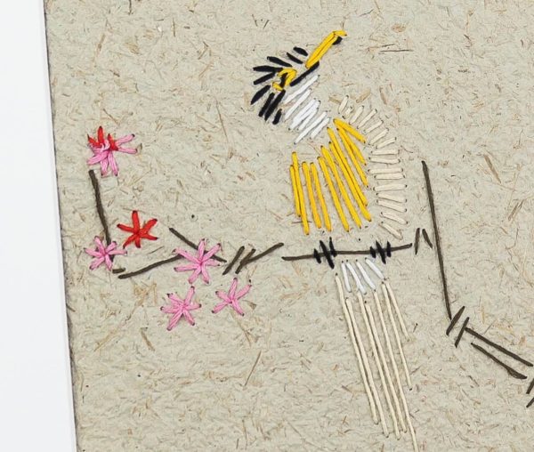 artwork of a yellow bird sitting in a tree with pink and red flowers made using embroidery on handmade paper