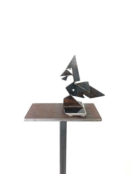metal sculpture of a waxwing bird displayed on a metal podium